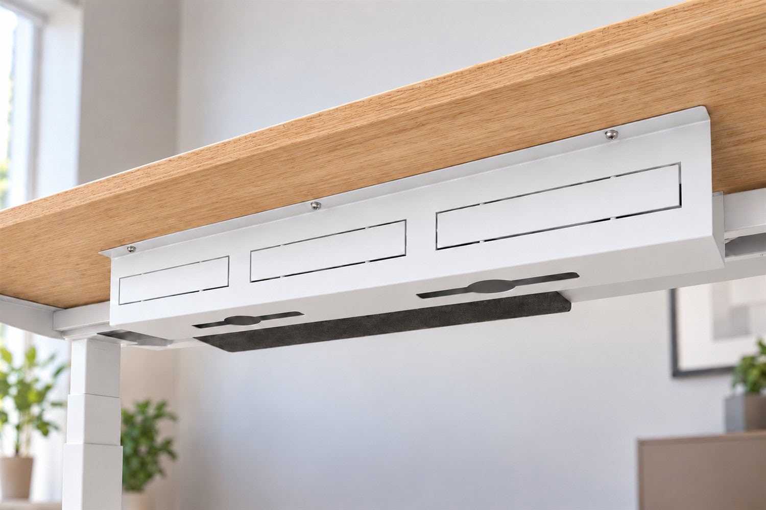 White cable management tray beneath an oak Stand Desk, with charcoal felt cable cover.